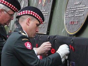 Lt-Col. Mark Pland places a poppy in memory of his brother, Cpl. Brent Poland, who was killed fighting in Afghanistan. Brent Poland and Pte. William Cushley, both of Sarnia-Lambton, were among those honoured at the dedication Sunday, in Sarnia's Veteran's Park, of a decommissioned LAV III vehicle - as a memorial to soldiers who served in the War in Afghanistan. (Tyler Kula/Sarnia Observer)