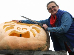 Rhonda Evans with her 411-pound pumpkin, carved into a spider jack-o'-lantern, at Glocca Morra Farms in Kingston on Sunday. (Steph Crosier/The Whig-Standard)