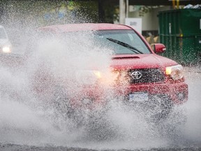 Drivers blast through flooded sections of a road near West Vancouver's Park Royal shopping centre in mid-October, as heavy rain pelted the metro area throughout the month. (Mark van Manen/PNG Files)
