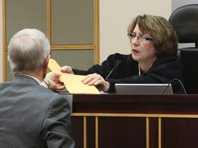 Darryl Bloodworth, left, an attorney for the City of Orlando, hands two envelopes containing 911 calls during the Pulse nightclub shooting to Circuit Judge Margaret Schreiber, Monday, Oct, 31, 2016, in Orlando, Fla. Schreiber on Monday ordered the city of Orlando to release audio recordings of the Pulse nightclub gunman talking to police dispatchers and negotiators. But she won't rule on releasing other 911 calls from the mass shooting until she has listened to them. (Red Huber/Orlando Sentinel via AP)