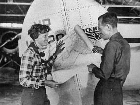 In this undated photo, aviator Amelia Earhart, left, and navigator Fred Noonan pose with a map of the Pacific Ocean showing the planned route of their round-the-world flight. (AP Photo)