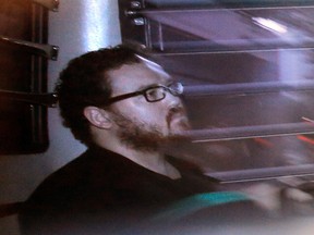In this Nov. 24, 2014, file photo taken through tinted glass, Rurik Jutting, a British banker, sits in a prison bus as he arrives at a court in Hong Kong. (AP Photo/Vincent Yu, File)