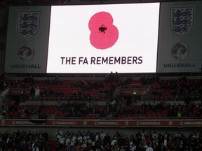 In this Saturday, Nov. 12, 2011 file photo, a poppy is displayed on a big screen for Armistice Day before the international friendly soccer match between England and Spain at Wembley Stadium in London. England and Scotland will face FIFA sanctions after insisting their players will wear black armbands with embroidered poppies to honor Britain's war dead for a match between the neighbors.  (AP Photo/Kirsty Wigglesworth, file)