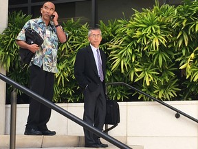 Kauai Community Correctional Center Warden Neal Wagatsuma, left, uses a cellphone while walking out of U.S. District Court in Honolulu on Tuesday, Nov. 1, 2016, with Hawaii Deputy Attorney General Nelson Nabeta. Trial has started in a lawsuit that alleges Wagatsuma subjected female inmates to sexual humiliation and discrimination. (AP Photo/Jennifer Sinco Kelleher)