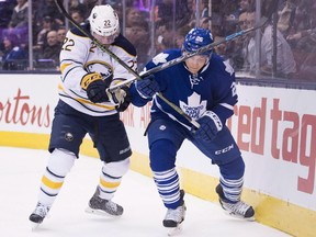 Toronto Maple Leafs' right wing Ben Smith and Buffalo Sabres' left wing Johan Larsson battle for the puck during first period NHL hockey action in Toronto on Saturday, March 19, 2016. (THE CANADIAN PRESS/Nathan Denette)