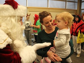 One-year-old Nevaeh Oxbro-McDonald, in the arms of mom Krystal Oxbro, isn't quite sure what to make of the bearded guy in red who paid a visit to the kick-off on Thursday in Kingston of the annual Christmas fundraising appeal by the local family and children's services agency. (Michael Lea/The Whig-Standard)