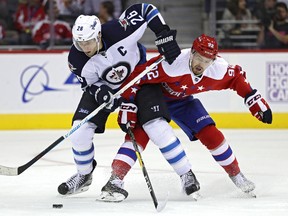 Evgeny Kuznetsov of the Capitals and Blake Wheeler of the Jets battle for the puck. (Patrick Smith/Getty Images)