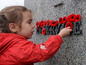 A new poll suggests Canadians would like to see efforts to honour fallen soldiers extend well beyond Remembrance Day. Joelle Choueiry, 3, of Ottawa, places a poppy on the National War Memorial following the Remembrance Day ceremony, in Ottawa in a November 11, 2015, file photo. (THE CANADIAN PRESS/Sean Kilpatrick)