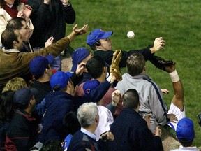 In this Oct 14, 2003, file photo, Steve Bartman catches a ball as Chicago Cubs left fielder Moises Alou’s arm is seen reaching into the stands, at right, against the Florida Marlins during Game 6 of the NLCS Tuesday, Oct. 14, 2003, at Wrigley Field in Chicago. (AP Photo/Morry Gash, File)