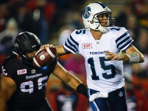 Toronto Argonauts quarterback Ricky Ray looks for a receiver as Calgary Stampeders' Zach Minter defends during first half CFL football action in Calgary, Friday, Oct. 21, 2016.