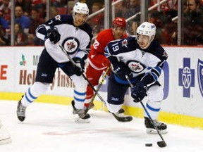 DETROIT, MI - NOVEMBER 04: Nic Petan #19 of the Winnipeg Jets looks for a open teammate in front of Andreas Athanasiou #72 of the Detroit Red Wings during the first period at Joe Louis Arena on November 4, 2016 in Detroit, Michigan. (Photo by Gregory Shamus/Getty Images)