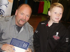 Former Toronto Maple Leafs captain Wendel Clark signs a book for 10-year-old Jordan McLaughlin on Friday at Walmart. (Paul Svoboda/The Intelligencer)
