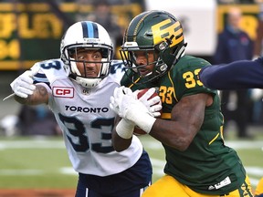 Edmonton Eskimos Shakir Bell (33) has a big gain on a run as Toronto Argonauts Aaron Berry (33) and Devin Smith (19) try to catch him during CFL action at Commonwealth Stadium in Edmonton, Saturday, November 5, 2016.
