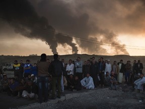 Men are held by Iraqi national security agents, to be interrogated at a checkpoint, as oil fields burn in Qayara, south of Mosul, Iraq, Saturday, Nov. 5, 2016. Islamic State fighters launch counterattacks in the thin strip of territory Iraqi special forces have recaptured in eastern Mosul, highlighting the challenges ahead as the battle moves into more densely populated neighborhoods where coalition air power must be used more selectively. (AP Photo/Felipe Dana)