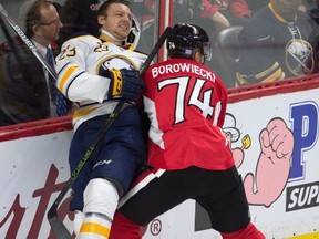 Ottawa Senators defenceman Mark Borowiecki checks Buffalo Sabres centre Sam Reinhart into the boards on Nov. 5. (THE CANADIAN PRESS/Adrian Wyld)