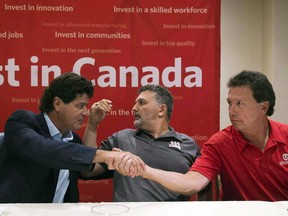 The union representing 6,700 autoworkers at Ford in Canada said it has reached a tentative agreement and secured a $700-million product investment from the automaker after a tense round of talks that went past the midnight deadline. Unifor national president Jerry Dias, left, shakes hands with bargaining committee member Chris Taylor, right, of Ford Motor Company, as bargaining committee member Dino Chiodo, of Fiat Chrysler, sits between them, after the conclusion of a news conference regarding the ongoing Canadian Auto Workers union talks, in Toronto in an August 11, 2016, file photo. THE CANADIAN PRESS/Nathan Denette