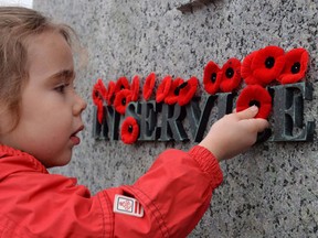 Joelle Choueiry, 3, of Ottawa, places a poppy on the National War Memorial following the Remembrance Day ceremony, in Ottawa in a November 11, 2015, file photo. (THE CANADIAN PRESS/Sean Kilpatrick)