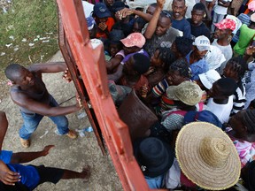 Security closes the gate on people trying to enter a yard where food distribution was to take place, in Maniche, Haiti, Monday, Oct. 17, 2016.