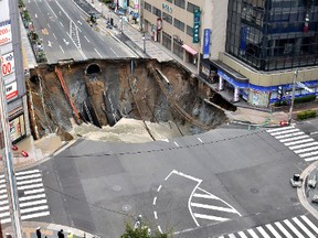 A massive shinkhole is created in the middle of the business district in Fukuoka, southern Japan Tuesday, Nov. 8, 2016. Parts of a main street have collapsed in the city, creating a huge sinkhole and cutting off power, water and gas supplies to parts of the city. Authorities said no injuries were reported from Tuesday's pre-sunrise collapse in downtown Fukuoka. (Kyodo News via AP)