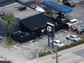 In this June 12, 2016 file photo, law enforcement officials work at the Pulse gay nightclub in Orlando, Fla., following a mass shooting. The city of Orlando has announced plans to purchase the nightclub and convert it into a memorial. (AP Photo/Chris O'Meara, File)