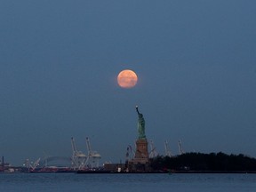 This Sunday, June 23, 2013 file photo shows a supermoon over the Statue of Liberty in New York. Monday, Nov. 14, 2016 will have the closest full moon of the year, or every 14 months to be precise. (AP Photo/Julio Cortez)