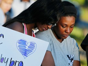 FILE – In this Sept. 15, 2016, file photo, relatives of Tyre King, a 13-year-old Ohio boy fatally shot by Columbus police on Sept. 14, 2016, console each other during a vigil in Columbus, Ohio. Tyre King was struck three times on the left side of his head, chest and abdomen, according to an autopsy report released Thursday, Nov. 10, 2016, by Franklin County Coroner Dr. Anahi Ortiz. (AP Photo/Jay LaPrete, File)