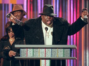 In this Dec. 6, 1995, file photo, The Notorious B.I.G., who won rap artist and rap single of the year, clutches his awards at the podium during the annual Billboard Music Awards in New York. (AP Photo/Mark Lennihan, File)