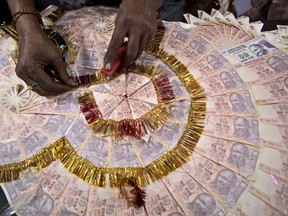 A shopkeeper prepares a garland with Indian 10 rupees denomination notes (USD $0.15) for sale, especially for wedding season, in Jammu, India, Friday, Nov. 11, 2016. Delivering one of India's biggest-ever economic upsets, Prime Minister Narendra Modi this week declared the bulk of Indian currency notes no longer held any value and told anyone holding those bills to take them to banks to deposit or exchange them. (AP Photo/Channi Anand)