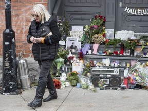 A woman walks away after placing flowers in front of the home of legendary singer and poet Leonard Cohen Friday, November 11, 2016 in Montreal. Cohen has died at the age of 82. THE CANADIAN PRESS/Paul Chiasson