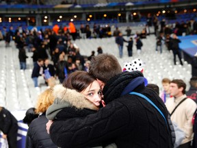 This is a Friday, Nov. 13, 2015 file photo of a supporter comforts a friend after invading the pitch of the Stade de France stadium at the end of the international friendly soccer match between France and Germany in Saint Denis, outside Paris. Sunday marks the anniversary of the Nov. 13, deadly attacks in Paris. (AP Photo/Christophe Ena)