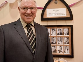 Pastor Glen Carlson, a pastor of the Immanuel Lutheran Church of Rosenthal for 37 years, stands next to a plaque of former pastors on Sunday, Nov. 6, 2016 - Photo by Yasmin Mayne.