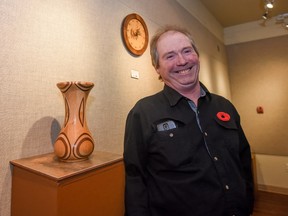 Lyle Zutz poses next to the first vase he ever made during his exhibit's opening at the Melcor Cultural Centre in Spruce Grove on Saturday, Nov. 5, 2016. Zutz lost his job in heavy industry because of an injury, but found a new passion in creating vases - Photo by Yasmin Mayne.