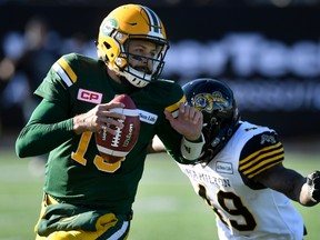 Edmonton Eskimos' Mike Reilly (30) gets flushed out of the pocket by Hamilton Tiger Cats' Larry Dean (49) during first half CFL playoff action, in Hamilton, Ont., on Sunday, November 13, 2016. (THE CANADIAN PRESS/Frank Gunn)