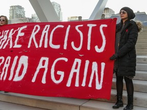 Anti-Trump protesters hold a sign at City Hall on Sunday. (DAVE THOMAS, Toronto Sun)