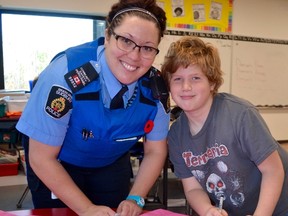 Krystle Beausoleil, police youth safety co-ordinator, and St. David School Grade 3 student, Mathew Tremblay, sign a pink shirt to support the Pink Shirt Campaign. Supplied photo