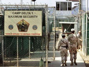 In this June 27, 2006 file photo, reviewed by a U.S. Department of Defense official, U.S. military guards walk within Camp Delta military-run prison, at the Guantanamo Bay U.S. Naval Base, Cuba. (AP Photo/Brennan Linsley, File)