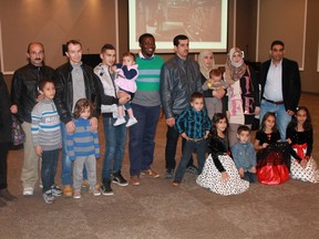 Local, award-winning photographer Bisi Alawode (centre) stands with some of the Syrian refugee families he took pictures of during his Nov. 4 photography exhibition, Beyond Now.
CARL HNATYSHYN/SARNIA THIS WEEK