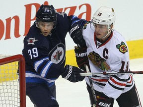 Winnipeg Jets defenceman Toby Enstrom (left) ties up Chicago Blackhawks centre Jonathan Toews. (Brian Donogh/Winnipeg Sun file photo)