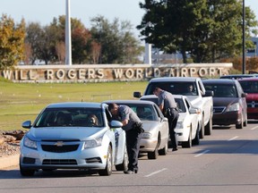 Oklahoma City police officers gather information from vehicles leaving Will Rogers World Airport, Tuesday, Nov. 15 2016, in Oklahoma City. The airport was put on lockdown after a shooting at the main terminal. (Steve Gooch/The Oklahoman via AP)