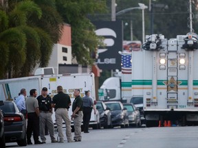 Law enforcement officials confer near the Pulse Orlando nightclub before sunrise Monday, June 13, 2016, in Orlando, Fla. Pulse Orlando was the scene of a mass fatal shooting early Sunday morning. (AP Photo/Chris O'Meara)