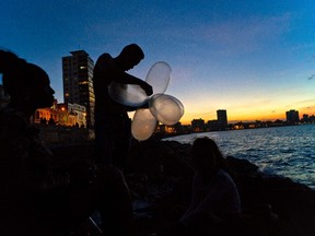 In this Nov. 13, 2016 photo, mechanic Junior Torres Lopez ties inflated condoms together for his fishing line to keep his bait high in the water and increase his line’s resistance against the pull of heavy fish, as his wife Edelmis Ferro Solano sits nearby along the malecon sea wall, at sunset in Havana, Cuba. Dozens of men can be found “balloon fishing” along the Havana seawall at night, using their homemade floats to carry their lines as far as 900 feet into the coastal waters. (AP Photo/Ramon Espinosa)