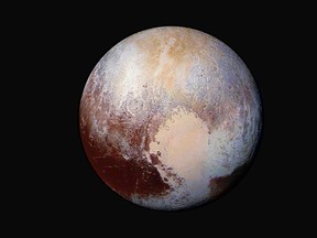 This image made available by NASA on Friday, July 24, 2015 shows a combination of images captured by the New Horizons spacecraft with enhanced colors to show differences in the composition and texture of Pluto's surface. On Wednesday, Nov. 16, 2016, scientists said that Pluto may have rolled over on its axis eons ago, the result of tidal forces with jumbo moon Charon, and that a subsurface sea is the most likely explanation. (NASA/JHUAPL/SwRI via AP)
