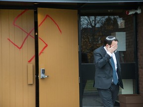 Joshua Dougherty wipes his eye as he comes through the doors at Congregation Machzikei Hadas, which was spraypainted with swastikas and hateful messages sometime over the night.