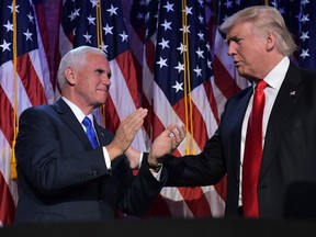 This file photo taken on November 9, 2016 shows Republican presidential elect Donald Trump (R) reaches to his Vice President elect Mike Pence during election night at the New York Hilton Midtown in New York. President-elect Donald Trump meets with running mate Mike Pence in New York on November 15, 2016 to discuss cabinet appointments amid reports of intense infighting over choice posts. / MANDEL NGANMANDEL NGAN/Getty Images