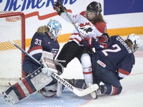 Team Canada's Rebecca Johnston is sandwiched between Team USA goaltender Alex Rigby and Lee Stecklein during second-period gold-medal action at the women's world hockey championships earlier this year in Kamloops, B.C. Hockey Canada is bringing its national women's team to Sarnia in mid-December for a series of practices and an exhibition game against its American counterpart Dec. 19 at Progressive Auto Sales Arena. (THE CANADIAN PRESS/Ryan Remiorz)