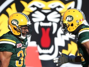 John White, left, celebrates a touchdown against the Tiger-Cats Sunday with cornerback Garry Peters Sunday in Hamilton. (The Canadian Press)
