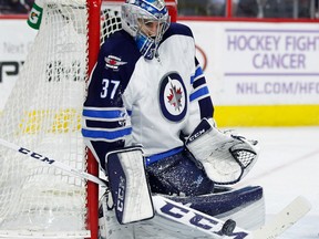 Connor Hellebuyck deflects the puck away with his stick during the second period of Thursday night's game in Philadelphia. (AP Photo/Tom Mihalek)
