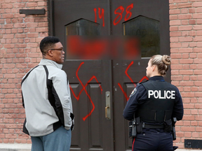 Hate graffiti on Parkdale United Church in Ottawa , November 18, 2016.  
Reverend Dr. Anthony Bailey with police officer. (Jean Levac , Postmedia)