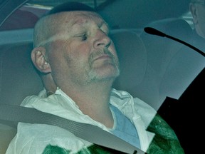 Richard Henry Bain sits with his eyes closed in the back of a police car, as he arrives at the Montreal courthouse, Thursday Sept. 6, 2012.   (Phil Carpenter/POSTMEDIA FILE PHOTO)
