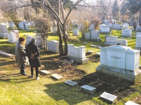 Two women stand at the grave of legendary singer and poet Leonard Cohen where he was buried at the family plot in the Shaar Hashomayim cemetery, in Montreal (Canadian Press)